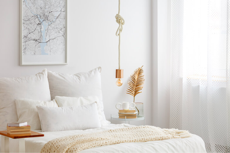 Light,white bedroom interior and small side tables with books on top as well as gold decorative items